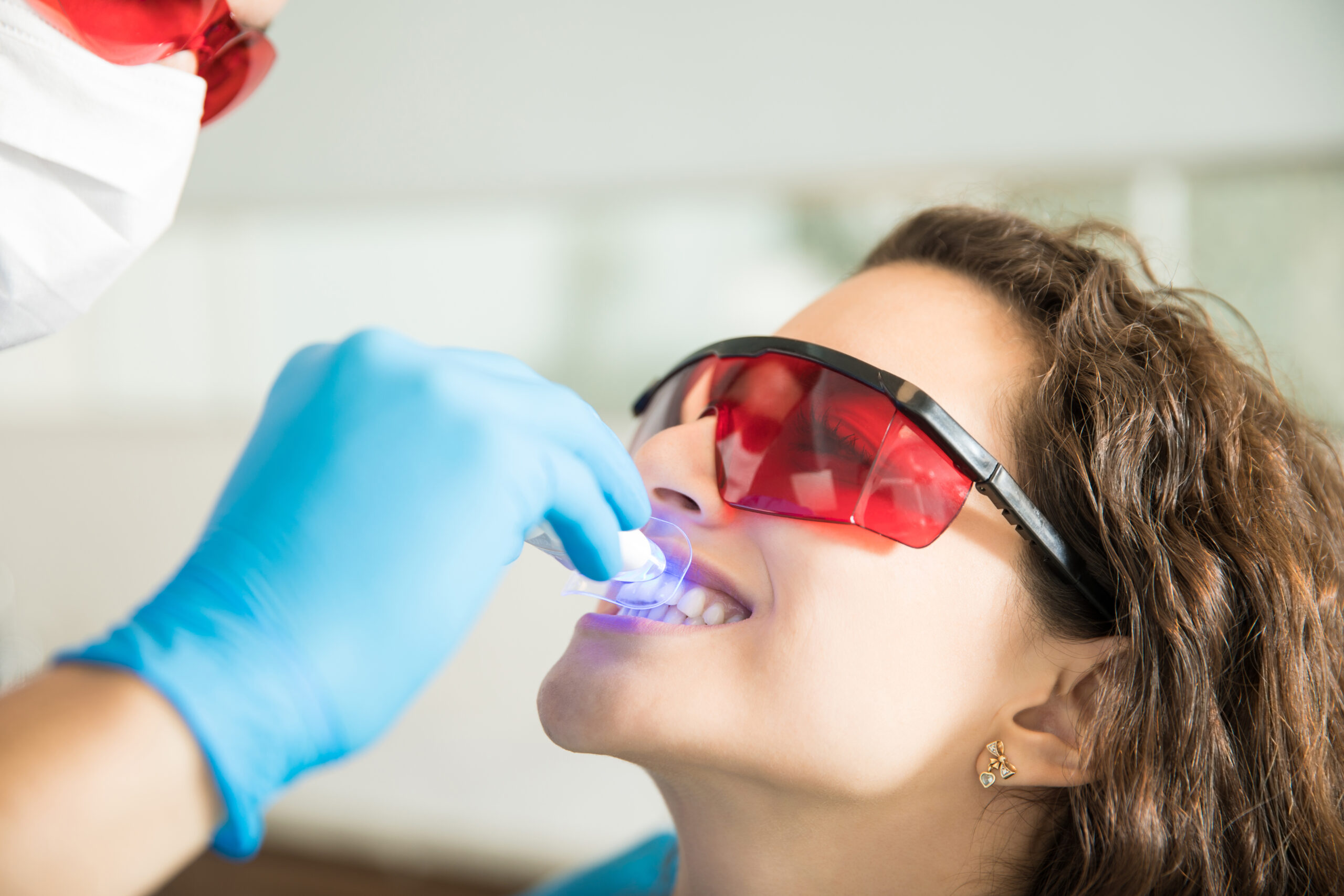 Services woman having dental checkup with ultraviolet light